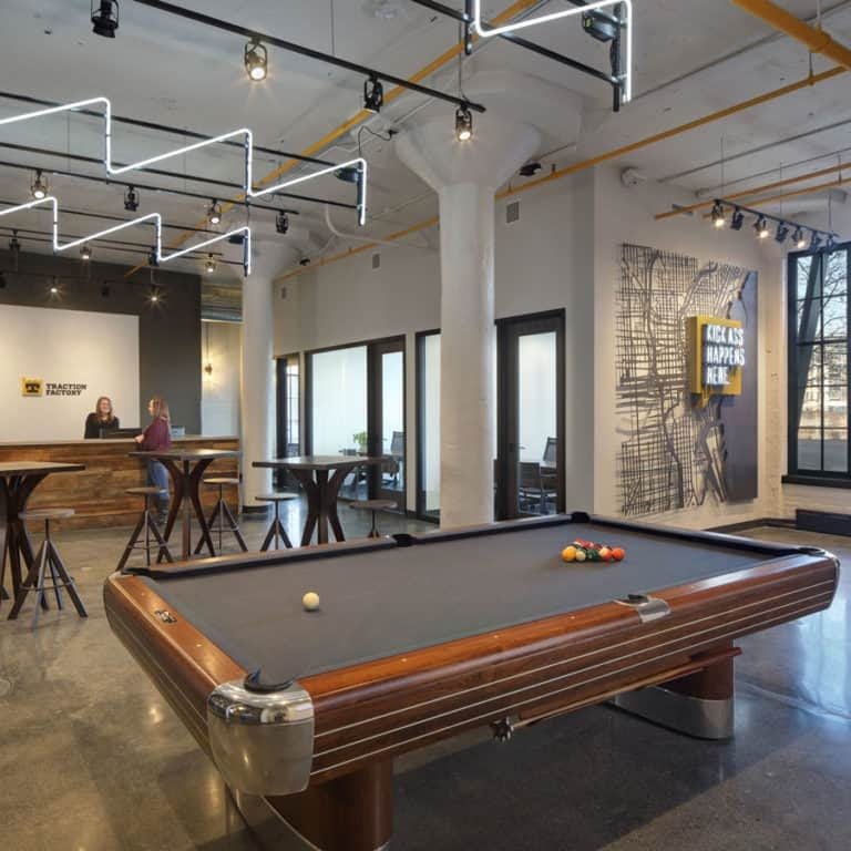 This space features pub tables, stools, a pool table and a mounted television creating a relaxed environment