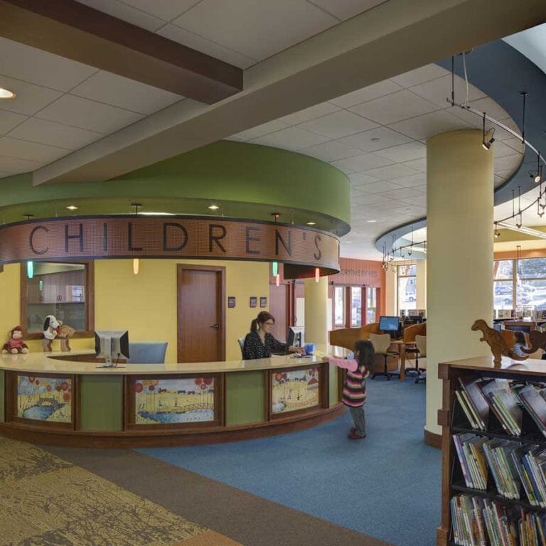 Jack Russell Memorial Library Children's Reference Desk highlights the welcome nature and features custom artwork at child-eye-height that illustrates local history and culture and hidden aspirational words.