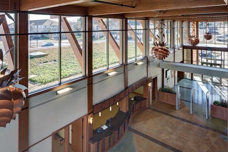 The view from the second floor the first floor library transaction desk is dominated by natural light and views towards the Green Living Roof used as a discussion point about sustainable design at the Jack Russell Memorial Library designed by plunkett Raysich Architects.
