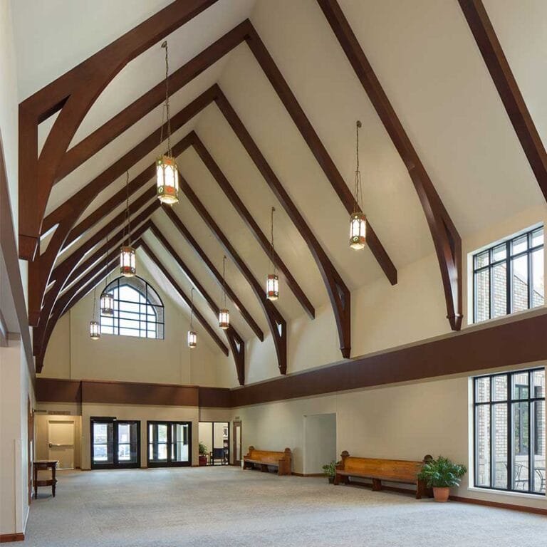 St. Clare of Assisi Catholic Church in Monroe, Wisconsin features a flexible Fellowship Hall that references traditional Catholic Architecture with pointed arched windows, and heavy timber construction